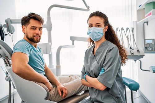 Dental team member smiling next to a patient in the dental chair