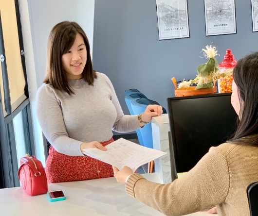 Dental patient handing paperwork to a receptionist