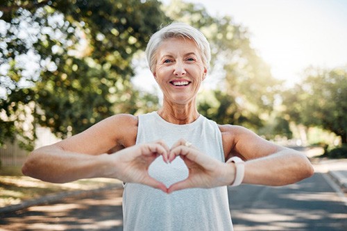 Lady smiles while forming the shape of a heart with hands
