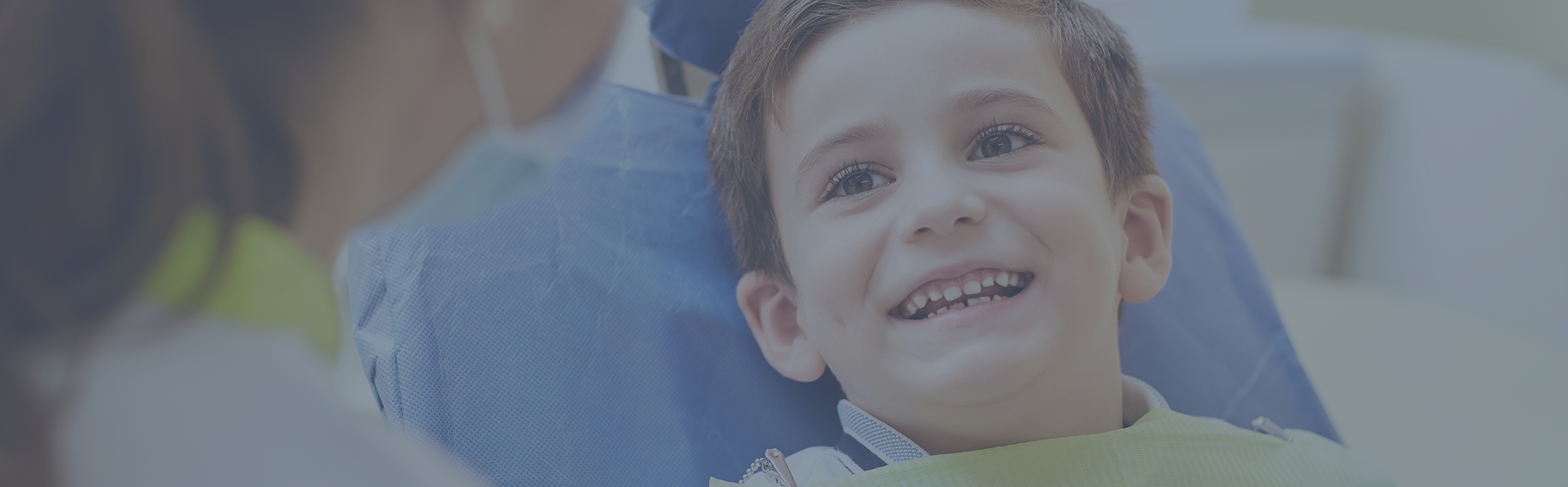 Young boy in the dental chair grinning at his dentist
