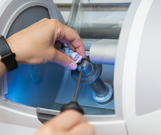 Dental professional adjusting a dental crown in a machine