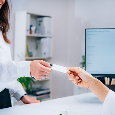 Dental patient handing their payment card to a team member