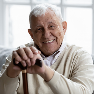 Smiling senior man sitting and leaning on his cane