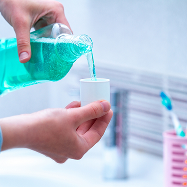 Pouring mouthwash into the bottle cap