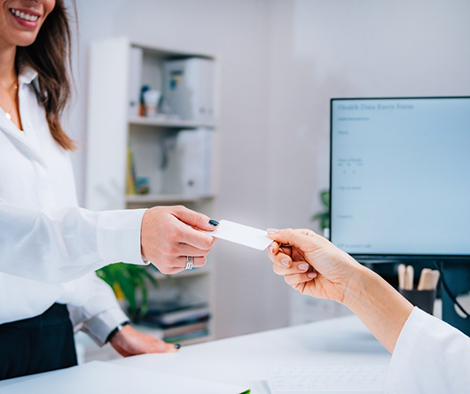 Dental patient handing their insurance card to a receptionist