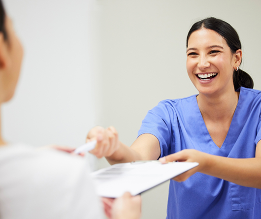 Dental team member handing a clipboard to a patient