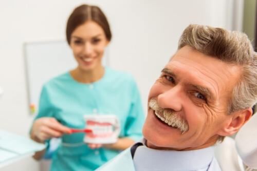 Senior man in dental chair getting dentures in Pecan Grove