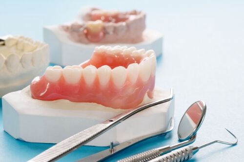 Models of teeth with dentures and dental instruments on table