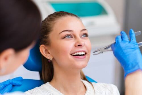 Woman in dental chair smiling before tooth extractions in Pecan Grove