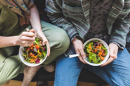 Bird’s eye view of two people holding salads in their laps