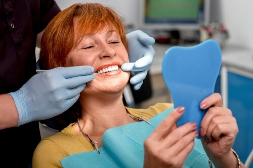 Dental patient admiring her new smile with dental implants in Pecan Grove