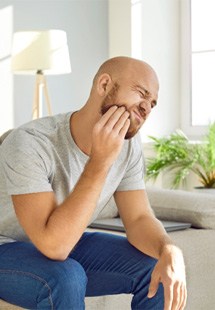 man sitting on couch with jaw pain 