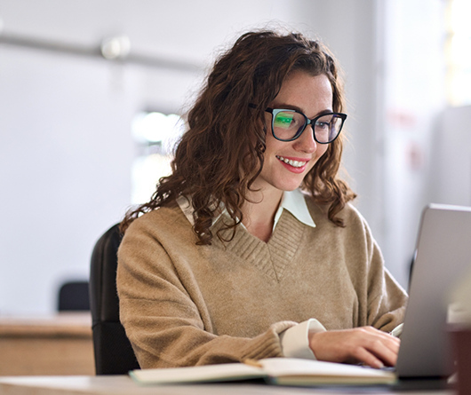 Young woman in a tan sweater using a laptop