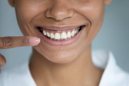 Person pointing to their smile after gum disease treatment in Pecan Grove