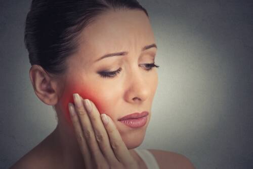 Woman holding her cheek in pain