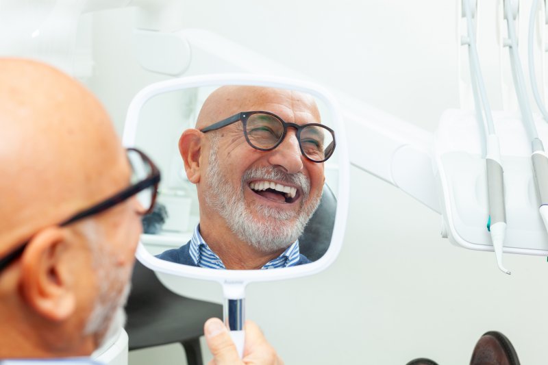 A senior man admiring the new dental implant in his mouth
