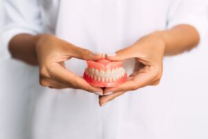 Person holding a set of dentures.