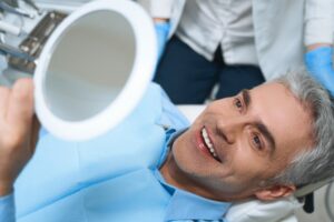 man looking at his dental implants in the mirror and smiling