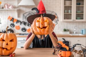 Person holding a jack-o’-lantern over their face